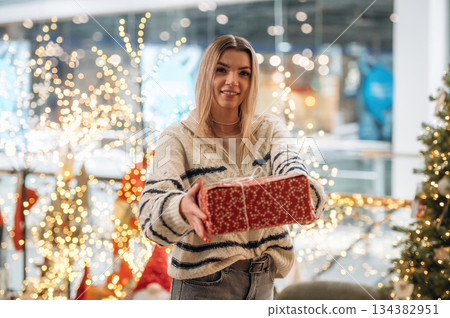 Big box in hands. Woman is with new year gifts near the Christmas tree 134382951