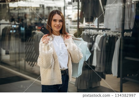 Holding credit card. Beautiful woman is in the mall, conception of shopping Holding credit card. Beautiful woman is in the mall, conception of shopping 134382997