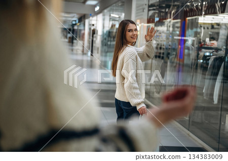 Two women are in the mall, showing goodbye hands gesture 134383009