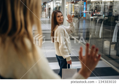 Two women are in the mall, showing goodbye hands gesture Two women are in the mall, showing goodbye hands gesture 134383010