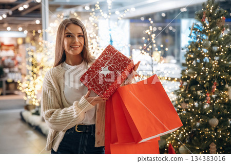 Holding bags. New year shopping and presents. Woman is near the Christmas tree 134383016