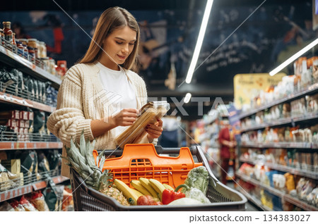 Cart is full. Beautiful woman is in the supermarket 134383027
