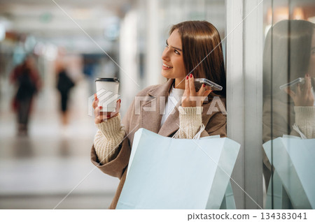 Talking by phone. Beautiful woman is in the mall, conception of shopping Talking by phone. Beautiful woman is in the mall, conception of shopping 134383041