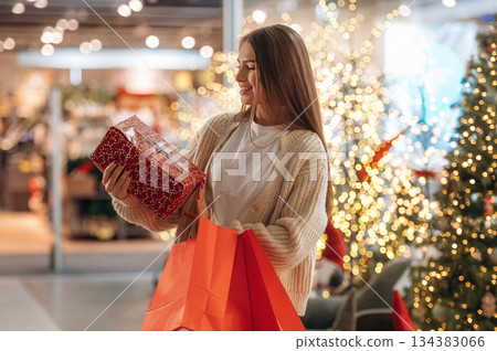 What a surprise, box. New year shopping and presents. Woman is near the Christmas tree 134383066
