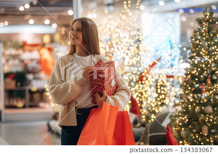 What a surprise, box. New year shopping and presents. Woman is near the Christmas tree 134383067