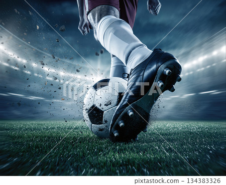 Soccer player strikes ball on field under stadium lights during night match 134383326