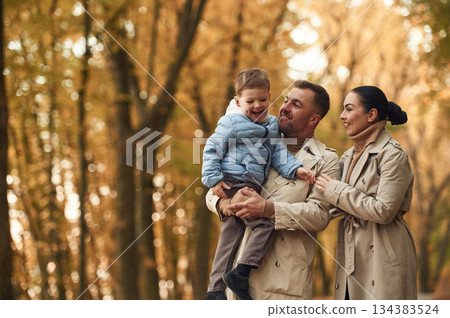 Happy family are together in the autumn forest near the road Happy family are together in the autumn forest near the road 134383524