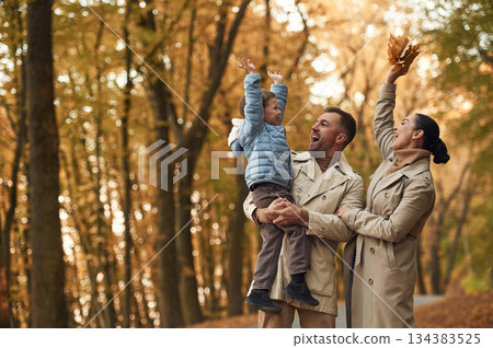 Happy family are together in the autumn forest near the road Happy family are together in the autumn forest near the road 134383525