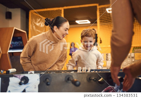 Having fun. Family of dad, mother and son that are playing table football game indoors Having fun. Family of dad, mother and son that are playing table football game indoors 134383531