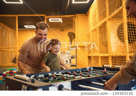 Weekend activities. Family of dad, mother and son that are playing table football game indoors 134383538