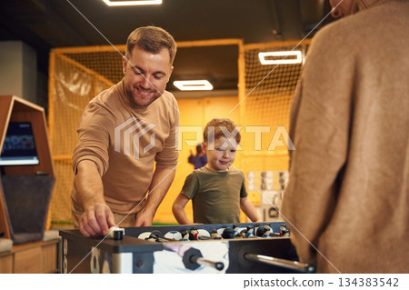 Playing table football game indoors. Family of dad, mother and son that are indoors 134383542