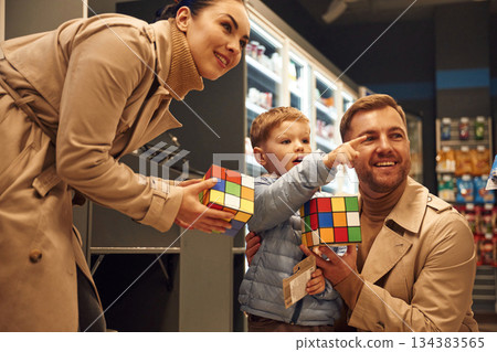 Looking far away. Family is in the toy shop, holding Rubik's cube 134383565