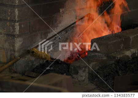 Flames and sparks burning in a swordsmith's forge 134383577