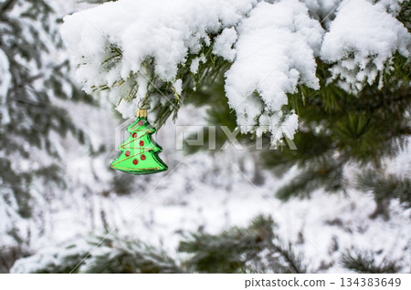 Christmas background with a Christmas toy on a snowy pine branch with a copy space 134383649
