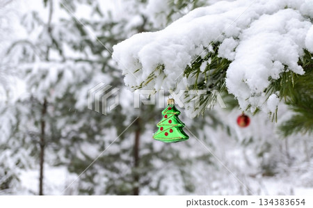 Christmas background with a Christmas toy on a snowy pine branch with a copy space Christmas background with a Christmas toy on a snowy pine branch with a copy space 134383654