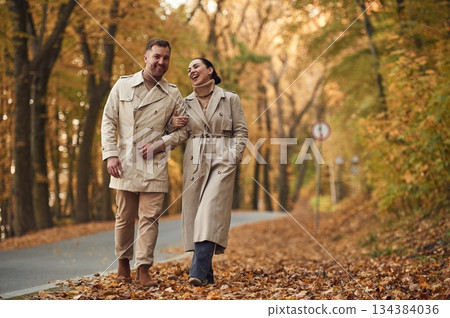 Smiling, hawing a walk. Lovely couple are together in the autumn forest near the road Smiling, hawing a walk. Lovely couple are together in the autumn forest near the road 134384036