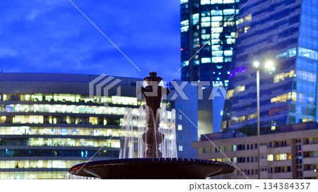 Office building in the evening with lightened workspaces. Modern, glazed skyscraper in financial district. Late hours in the office. Office building in the evening with lightened workspaces. Modern, glazed skyscraper in financial district. Late hours in the office. 134384357