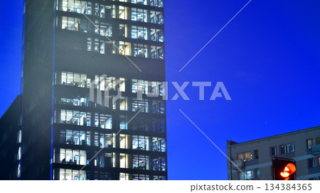 Office building in the evening with lightened workspaces. Modern, glazed skyscraper in financial district. Late hours in the office. Office building in the evening with lightened workspaces. Modern, glazed skyscraper in financial district. Late hours in the office. 134384365
