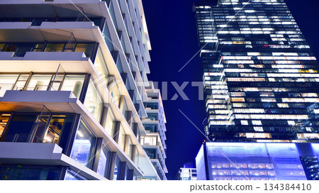 Office building in the evening with lightened workspaces. Modern, glazed skyscraper in financial district. Late hours in the office. Office building in the evening with lightened workspaces. Modern, glazed skyscraper in financial district. Late hours in the office. 134384410
