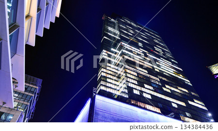 Office building in the evening with lightened workspaces. Modern, glazed skyscraper in financial district. Late hours in the office. Office building in the evening with lightened workspaces. Modern, glazed skyscraper in financial district. Late hours in the office. 134384436