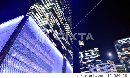 Office building in the evening with lightened workspaces. Modern, glazed skyscraper in financial district. Late hours in the office. Office building in the evening with lightened workspaces. Modern, glazed skyscraper in financial district. Late hours in the office. 134384438