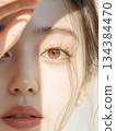 一位皮膚白皙的美麗年輕亞洲女性的特寫半臉美容/時尚鏡頭。光與影 134384470