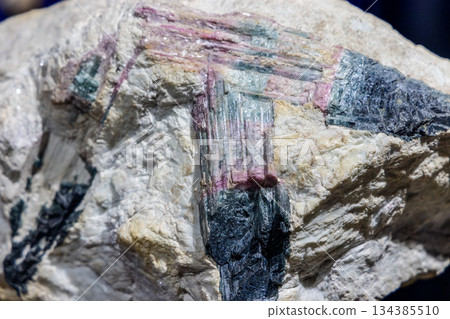Tourmaline in quartz mineral specimen showing elongated crystals with pink green black tones Tourmaline in quartz mineral specimen showing elongated crystals with pink green black tones 134385510