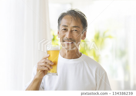 Smiling senior man holding a beer glass, looking at the camera 134386239