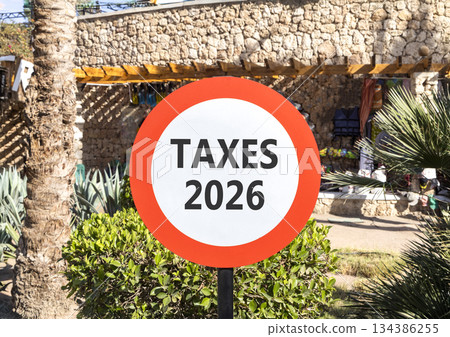 Taxes 2026 new year symbol. Concept words Taxes 2026 on beautiful white and red road sign. Beautiful palm trees palm-trees background. Business and taxes 2026 new year concept. Copy space Taxes 2026 new year symbol. Concept words Taxes 2026 on beautiful white and red road sign. Beautiful palm trees palm-trees background. Business and taxes 2026 new year concept. Copy space 134386255