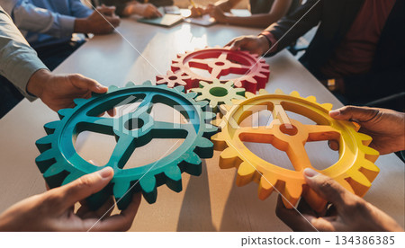 Group collaborates with colorful gears to solve problem in office setting during team meeting in afternoon hours 134386385