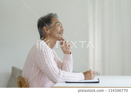 Senior man writing with a pen Senior man writing with a pen 134386770
