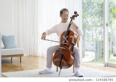 一位 60 多歲的男子正在拉大提琴 一位 60 多歲的男子正在拉大提琴 134386795