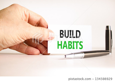 Build habits symbol. Concept word Build habits on beautiful white card. Beautiful black pen. Beautiful white paper background. Businessman's hand. Business build habits concept. Copy space. Build habits symbol. Concept word Build habits on beautiful white card. Beautiful black pen. Beautiful white paper background. Businessman's hand. Business build habits concept. Copy space. 134386929