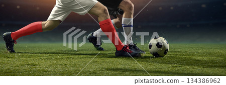 Physical football clash as rival players challenge for ball on pitch. 134386962