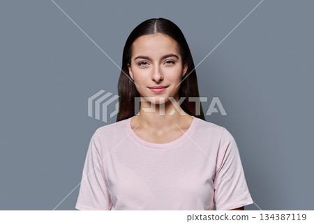 Portrait of beautiful smiling teenage girl against gray studio background Portrait of beautiful smiling teenage girl against gray studio background 134387119