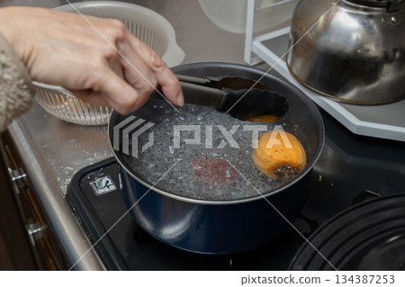 澀柿子透過浸入沸水中進行消毒,製成柿餅。 澀柿子透過浸入沸水中進行消毒,製成柿餅。 134387253