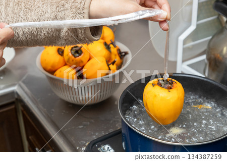 澀柿子透過浸入沸水中進行消毒,製成柿餅。 澀柿子透過浸入沸水中進行消毒,製成柿餅。 134387259