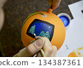 Female hands carefully painting a Christmas ball in vibrant orange hues 134387361