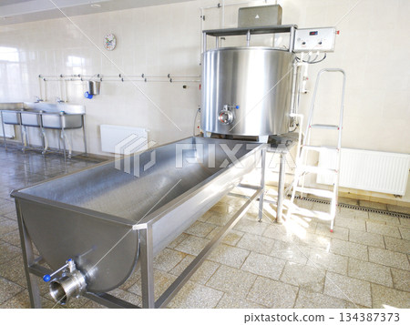 A cylindrical metal tank connected to a long rectangular bath. 134387373