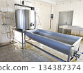 A cylindrical metal tank connected to a long rectangular bath. 134387374