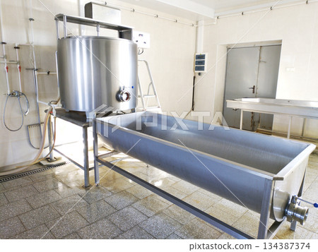 A cylindrical metal tank connected to a long rectangular bath. 134387374