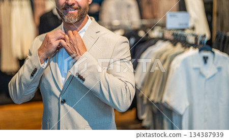 Male model suit boutique. Retail assistant help stylish man find suit. Stylish man in suit. Businessman choose elegant suit in store. Trendy jacket. Bespoke tailoring. Banner with cropped view Male model suit boutique. Retail assistant help stylish man find suit. Stylish man in suit. Businessman choose elegant suit in store. Trendy jacket. Bespoke tailoring. Banner with cropped view 134387939