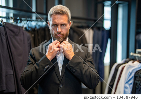 Stylish man in suit. Businessman choose elegant suit in store. Trendy suit jacket. Hispanic businessman choosing tailoring. Bespoke tailoring. Male model in suit boutique. Advertisement Stylish man in suit. Businessman choose elegant suit in store. Trendy suit jacket. Hispanic businessman choosing tailoring. Bespoke tailoring. Male model in suit boutique. Advertisement 134387940