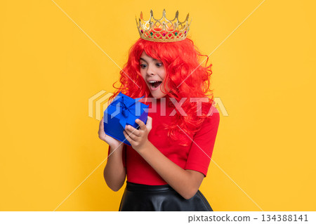 surprised child in crown with gift box on yellow background 134388141