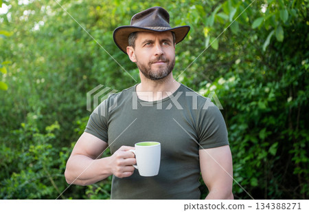 photo of cheerful cowboy man with coffee. cowboy man with coffee. cowboy man with coffee in hat. 134388271