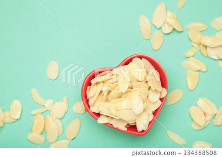 Fresh almond flakes in red plate on mint background 134388508