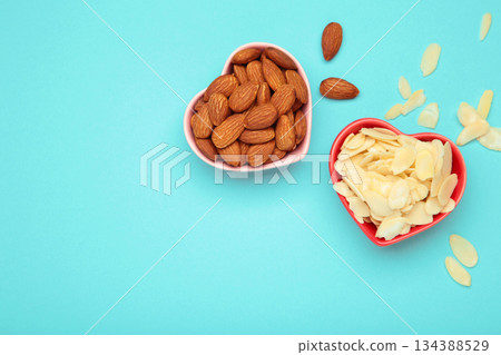 Fresh almond flakes and nuts in bowl on blue background 134388529