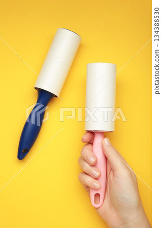 Woman holding lint roller on yellow background. Top view Woman holding lint roller on yellow background. Top view 134388530