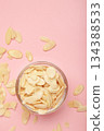 Fresh almond flakes in bowl on pink background. Vertical photo 134388533