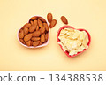 Fresh almond flakes and nuts in bowl on beige background 134388538